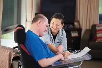 A person helping a man read a form. 