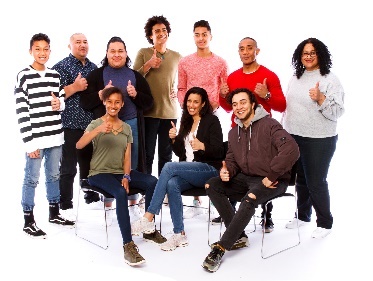 A group of diverse people sitting and standing together, all giving a thumbs up. 