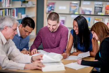 A group of diverse people studying together in a library. 