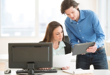 A man showing a woman a document. They work in the same office.