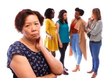 A sad woman being excluded from a group of people. 