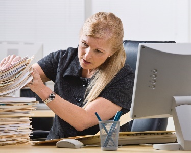 A woman going through a stack of files.
